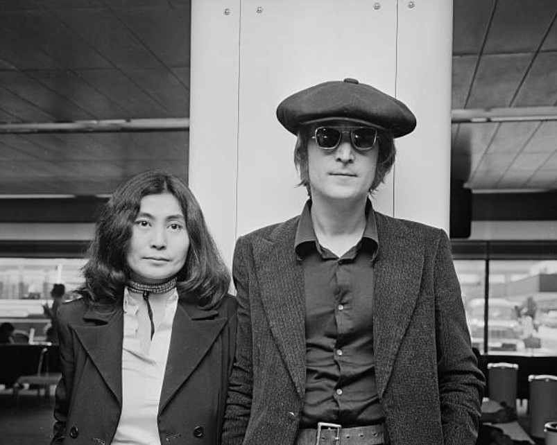 John Lennon and Yoko Ono arriving at London Airport from New York on July 14, 1971, captured in a candid moment.