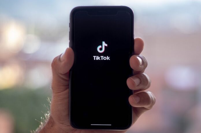 Hand holding a phone showing TikTok logo.